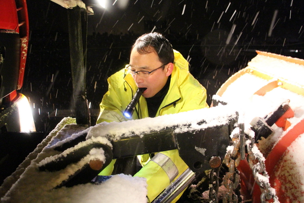 风雪中，马巢公司夜班除雪队员李夫胜正在调试除雪铲大灯.jpg